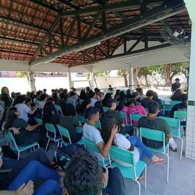 Alunos na Assembleia estudantil sentados em cadeiras em uma quadra.